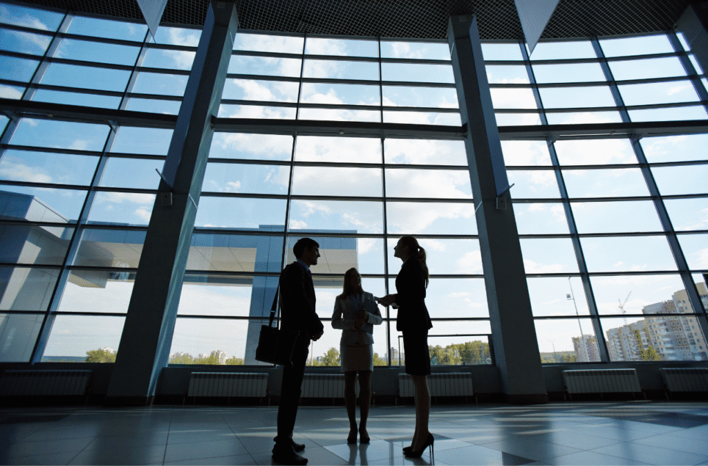 Three professionals in a modern business building discussing remote work opportunities.