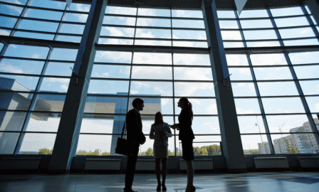 Three professionals in a modern business building discussing remote work opportunities.